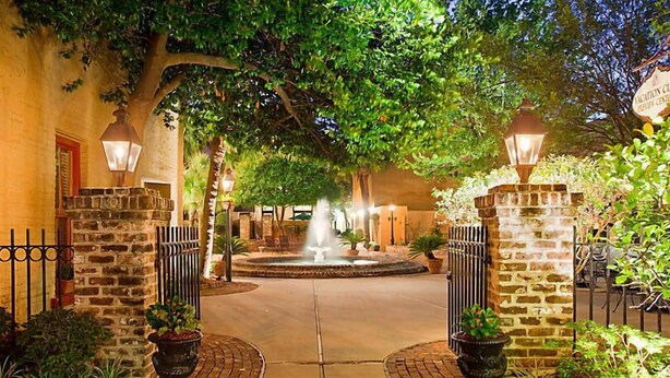 A courtyard with a fountain, stone walls, and potted plants. - The Lodge Alley Inn in the heart of Charleston! (Charleston)