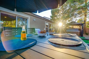 Eine Terrasse im Freien mit einem Tisch, der für eine Mahlzeit gedeckt ist, einer Getränkeflasche und Schalen mit Snacks.