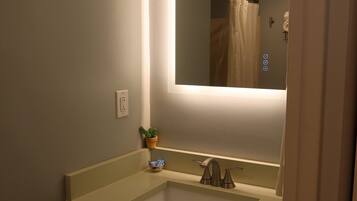 Een bad/douchecombinatie, een haardroger, handdoeken, zeep