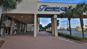The exterior of the Tidewater Beach Resort with a covered entrance, palm trees, and a clear sky.