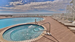 A swimming pool with a brick deck and lounge chairs.