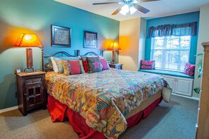 A bedroom with a bed, two bedside lamps, a window with curtains, and a ceiling fan. - Come Stay at Life`s a Hoot (Ruidoso)