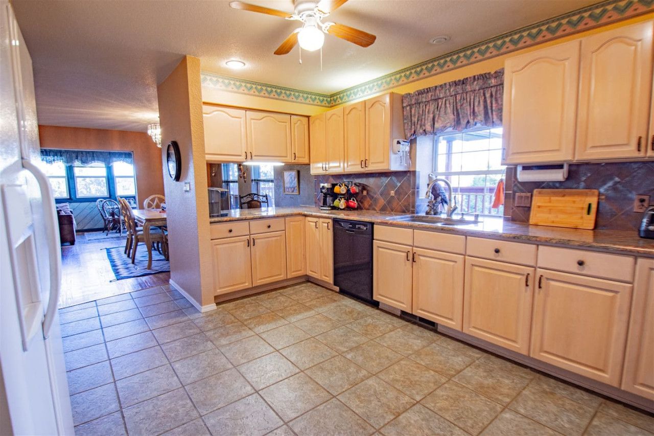 A kitchen with light wooden cabinets, a dishwasher, and a countertop with various kitchen items.