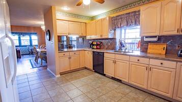 A kitchen with light wooden cabinets, a dishwasher, and a countertop with various kitchen items.