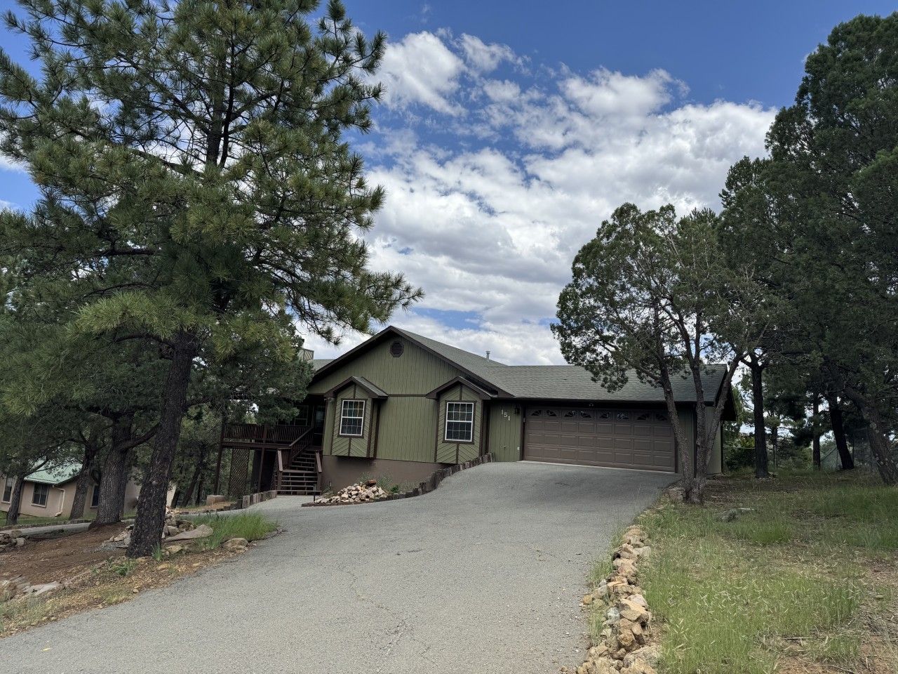 A single-story house with a sloped roof, a garage, and a driveway leading to the front door.