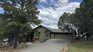 A single-story house with a sloped roof, a garage, and a driveway leading to the front door.