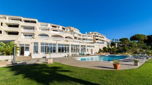 A hotel with a swimming pool, outdoor seating, and a well-maintained lawn.