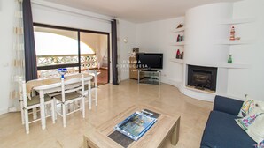 A modern living room with a dining area, a fireplace, and a TV.