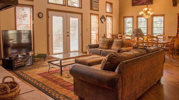 A spacious living room with a large television, comfortable seating, and a fireplace. - Horsin` Around - Unit M2 (Ruidoso)