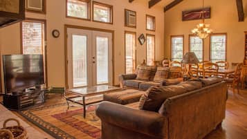A spacious living room with a large television, comfortable seating, and a fireplace.