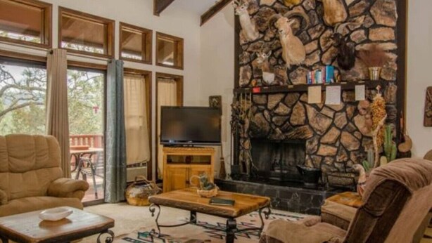 A cozy living room with a stone fireplace, leather sofas, and a flat-screen TV. - Come Stay in Antlers - D4 (Ruidoso)