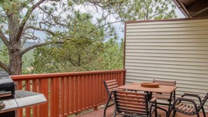 A wooden deck with a red railing, a table with four chairs, and a barbecue grill. - Come Stay in Antlers - D4 (Ruidoso)
