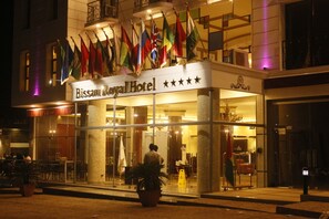 The exterior of Bissau Royal Hotel with multiple flags displayed outside.