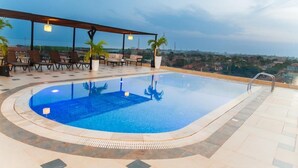 Piscina en la azotea con sillones de descanso y vistas de la ciudad.