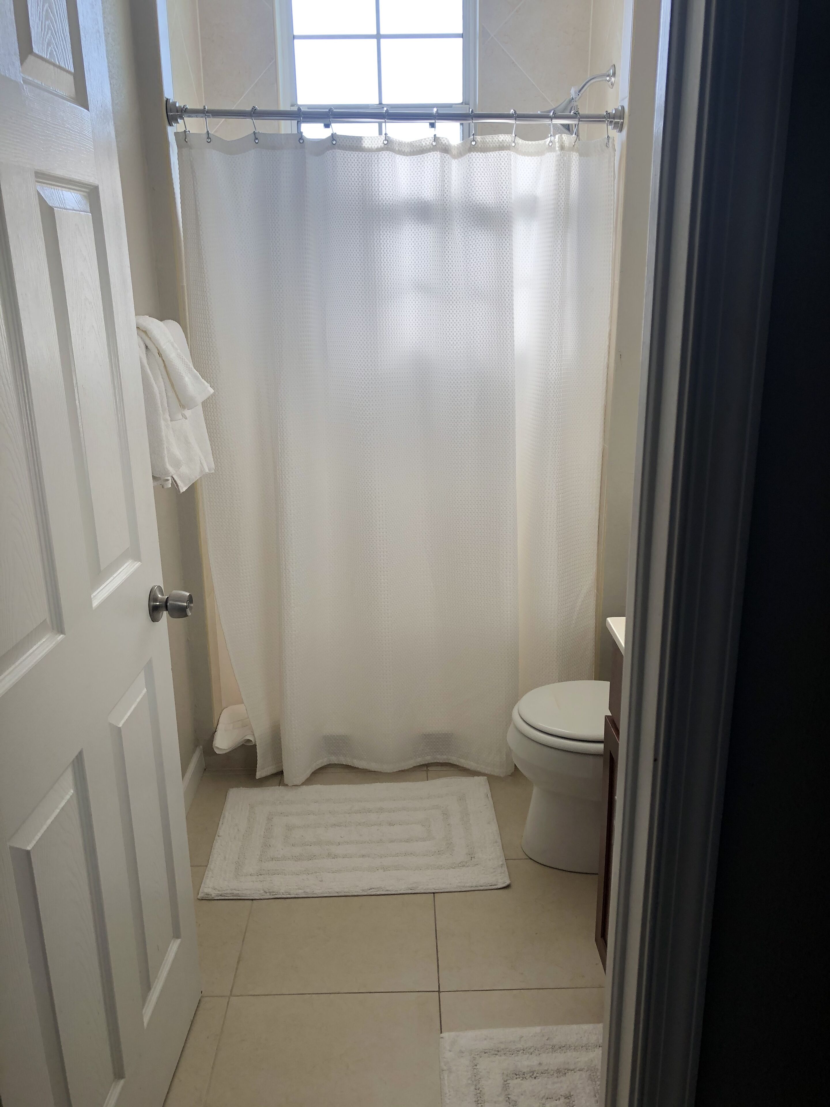 Une salle de bain avec un rideau de douche, des toilettes et un tapis.