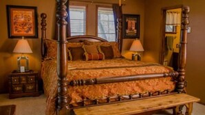 A traditional wooden four-poster bed with a bench, two bedside tables with lamps, and framed artwork on the walls. - Raw Hide Lodge - Unit M1 (Ruidoso)