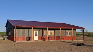 A single-story building with a red roof and a covered porch. - Quiet country getaway located within 10 minutes from town (Pratt)