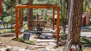 A wooden swing set in a forested area with a stone pathway.