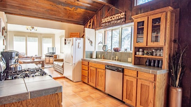 A rustic kitchen with wooden cabinets, a stove, and a sink.