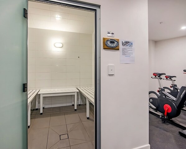 Ein Zimmer mit Sauna, einer Sitzbank, einem Wandheizkörper und einem stationären Fitnessrad.