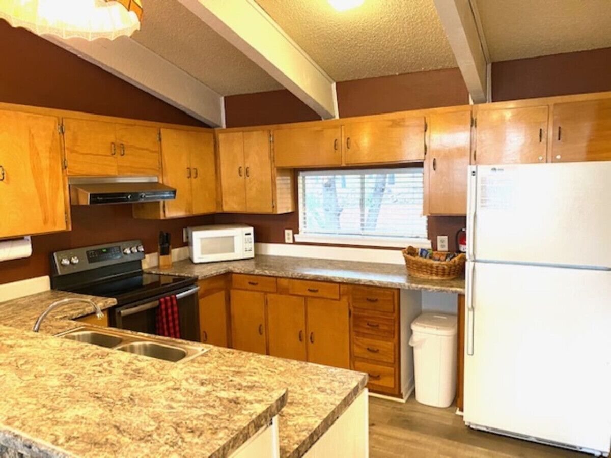 A compact kitchen with wooden cabinets, a stove, a microwave, and a refrigerator.