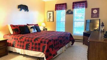 A bedroom with a bed, a nightstand, a dresser, a window with blinds, and a wall clock.