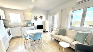 Et moderne køkken med spiseplads, en sofa og et fjernsyn.