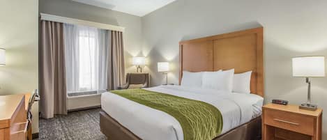 Une chambre d’hôtel avec un grand lit, des tables de chevet, un bureau et une chaise.