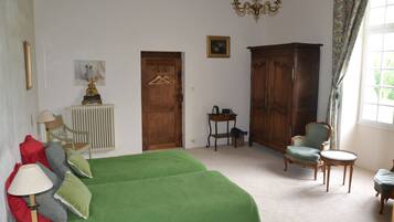 A bedroom with a bed, a chair, a table, and a wardrobe.