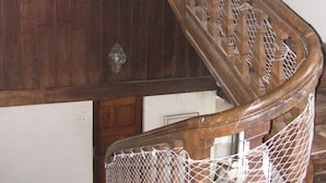 A wooden spiral staircase with a netted handrail, wooden walls, and a small window. - Malouinière des Trauchandières Saint-Malo (Saint-Jouan-des-Guerets)