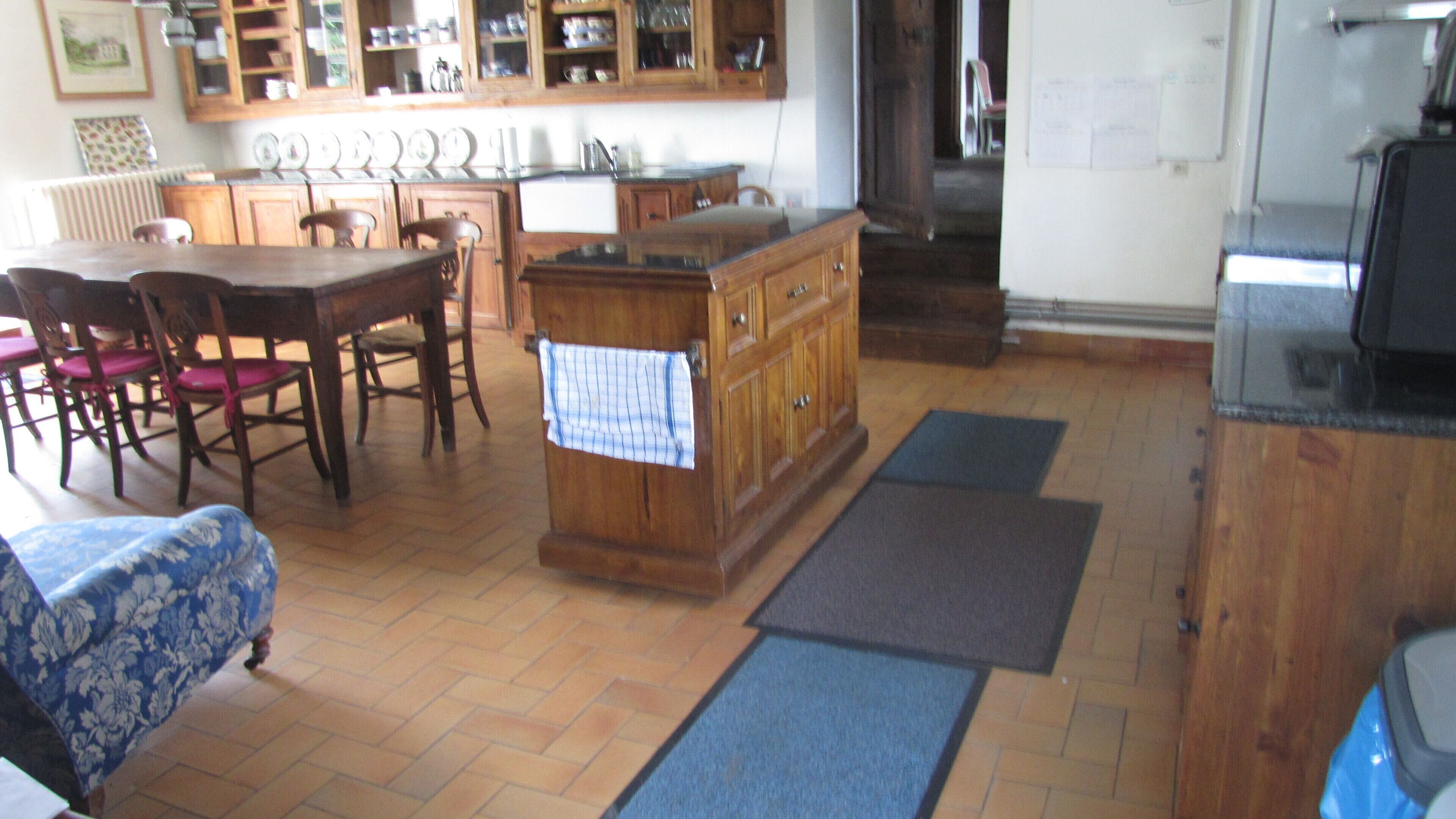 Una cocina con armarios de madera, una mesa de comedor con sillas y un tapete azul en el suelo.