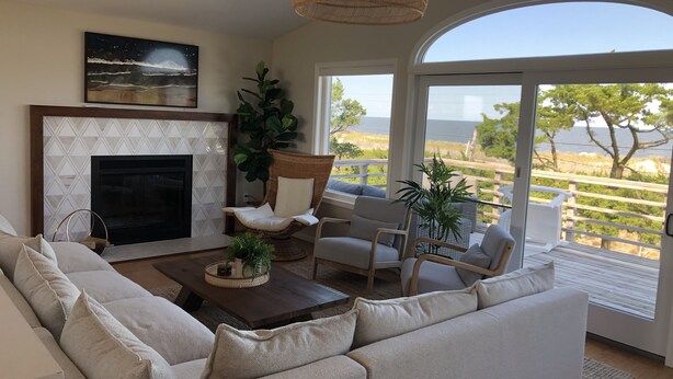 A living room with a fireplace, a large window with a view of the outdoors, and a comfortable seating area. - RARE Beachfront AND Wildlife Reserve Home in Broadkill Beach! (Milton)