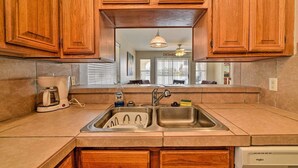 A kitchen with wooden cabinets, a double sink, a coffee maker, and a dishwasher.