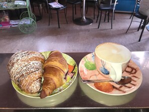 Een tafel met een croissant en een kop koffie op een schotel.