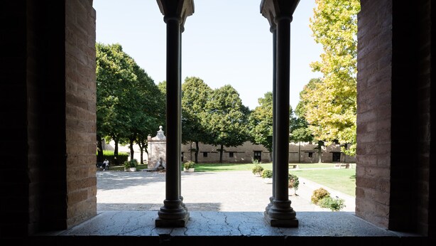 A courtyard with columns, a lawn, and a building in the background. - The House Of Mario (Monte San Pietrangeli)