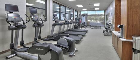Un gimnasio con cintas de correr, elípticas y máquinas de pesas.