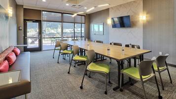 A conference room with a long table, chairs, a sofa, and a TV on the wall.
