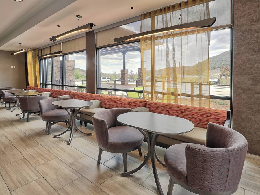 A modern interior with seating arrangements, large windows, and a view of the outdoors.
