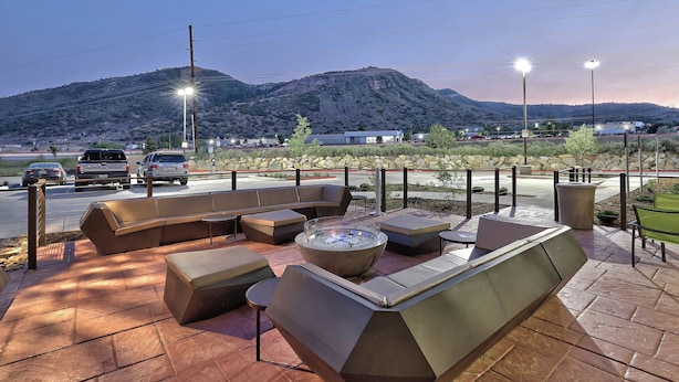 An outdoor seating area with a fire pit, stone walls, and a view of a mountain. - Springhill Suites by Marriott Durango (Durango)
