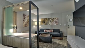 A modern hotel room with a bed, a sofa, a coffee table, and artwork on the walls. - Springhill Suites by Marriott Durango (Durango)