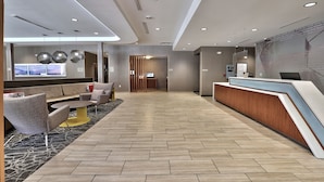 A modern hotel lobby with a reception desk, seating area, and a large window. - Springhill Suites by Marriott Durango (Durango)