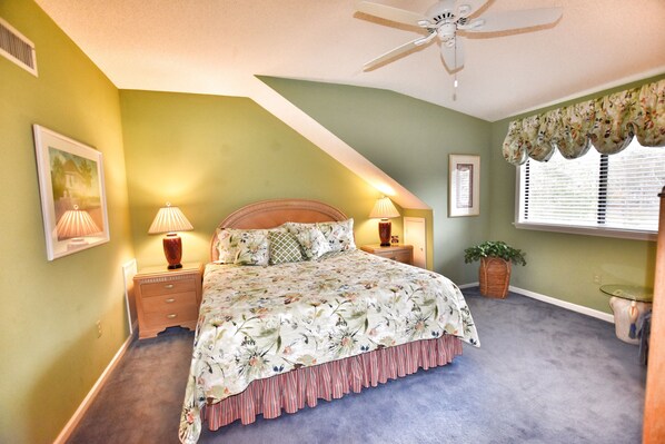 A bedroom with a bed, two bedside tables, a ceiling fan, a window with blinds, and a wall-mounted lamp. - Beautiful Lake View Villa in the Prestigious Kingston Plantation/Pools/Lakes (Myrtle Beach)