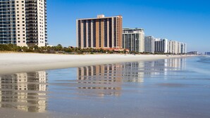 A beachfront hotel with multiple high-rise buildings, a sandy beach, and a clear sky. - Beautiful Lake View Villa in the Prestigious Kingston Plantation/Pools/Lakes (Myrtle Beach)