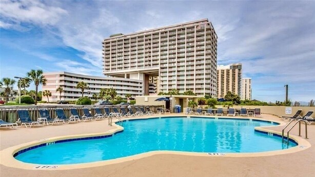 A hotel with a large pool area, multiple balconies, and a modern building design. - Beautiful Lake View Villa in the Prestigious Kingston Plantation/Pools/Lakes (Myrtle Beach)