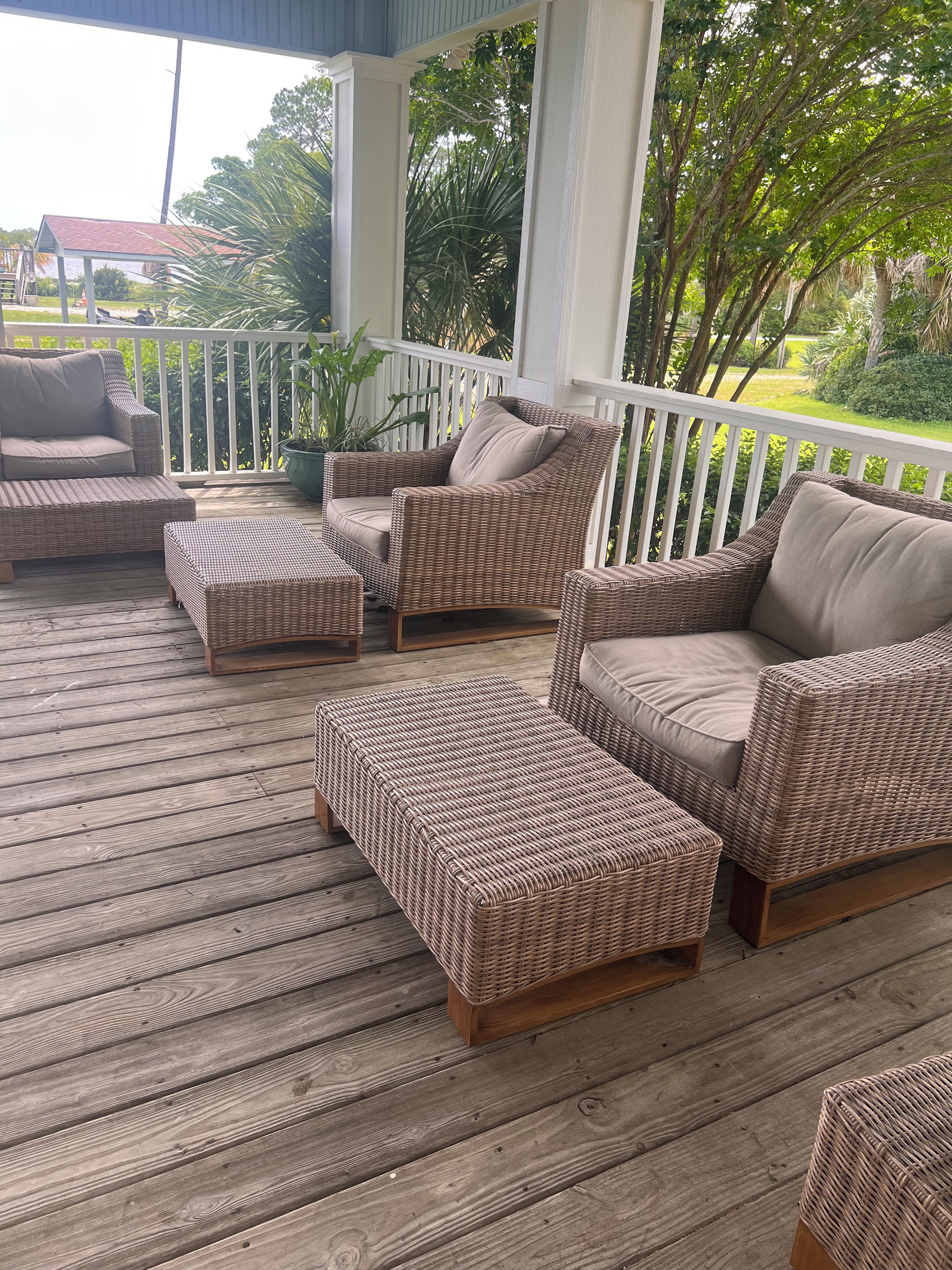 A covered outdoor seating area with wicker furniture and a wooden deck.
