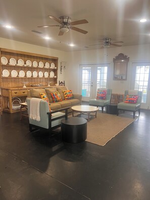 A living room with a sofa, armchairs, a coffee table, a ceiling fan, and a wall-mounted plate rack.