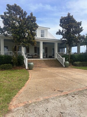 A two-story house with a porch, a staircase leading to the front door, and a clear sky.
