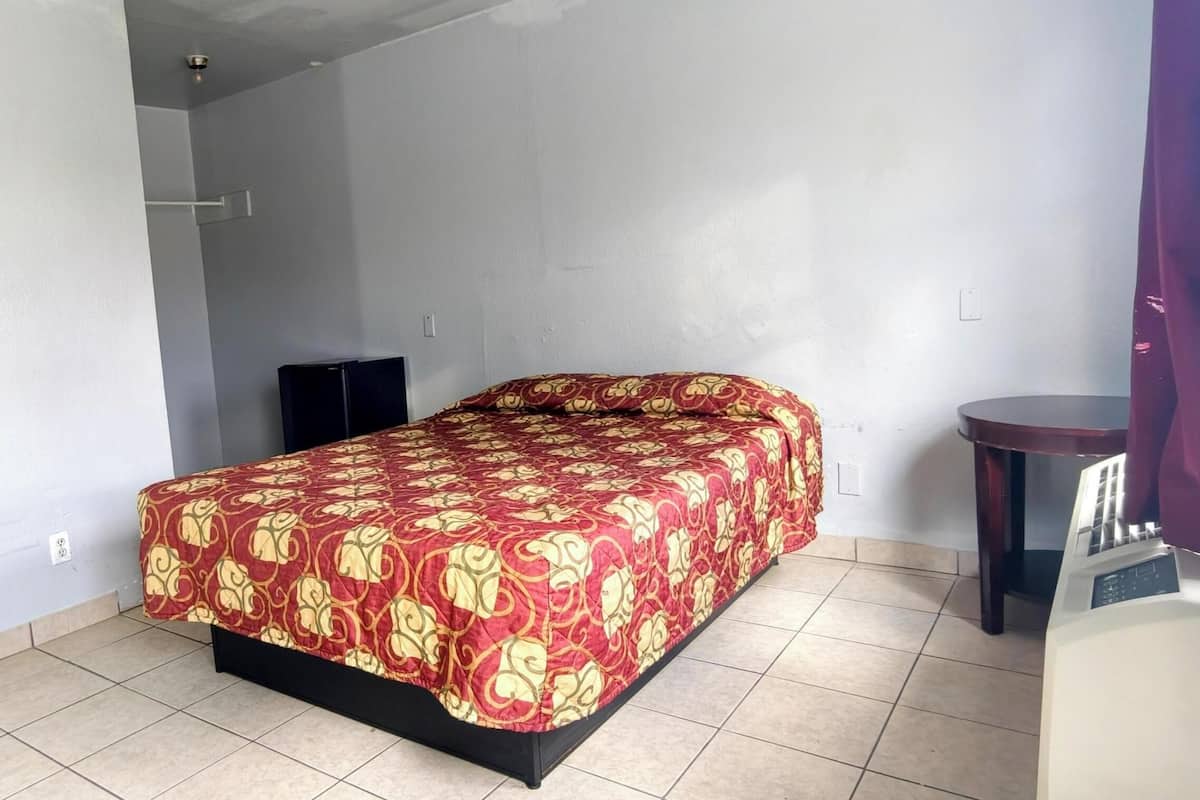A room with a bed, a small table, and a speaker.