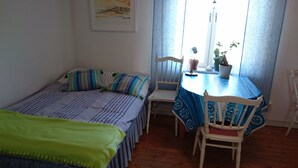 Een slaapkamer met een bed, een stoel, een tafel en een raam met gordijnen.