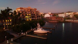 Ein Yachthafen mit einem vertäuten Boot, ein großes Hotel mit mehreren Balkonen und eine ruhige Uferpromenade.